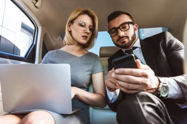 yakışıklı işadamı bir şey asistan arabada smartphone üzerinde gösterilen düşük açılı görünüş
