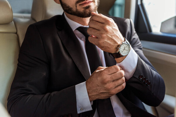 cropped image of businessman buttoning cuff in car