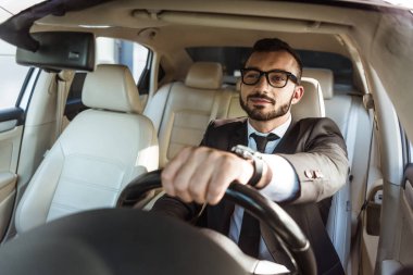 cheerful handsome driver in suit and glasses driving car clipart