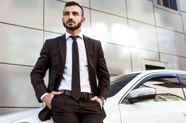 Arabanın üzerine eğilerek ve uzak seyir yakışıklı işadamı