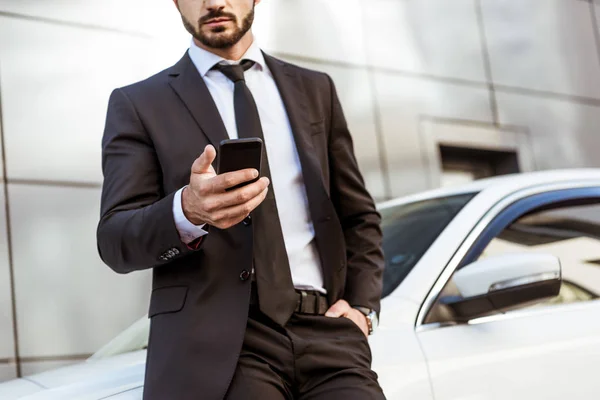 Przycięte Zdjęcie Biznesmena Trzymając Smartfon Stojący Pobliżu Samochodu — Zdjęcie stockowe