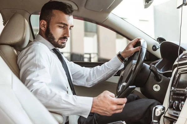 Motorista Bonito Camisa Carro Condução Olhando Para Smartphone — Fotografia de Stock