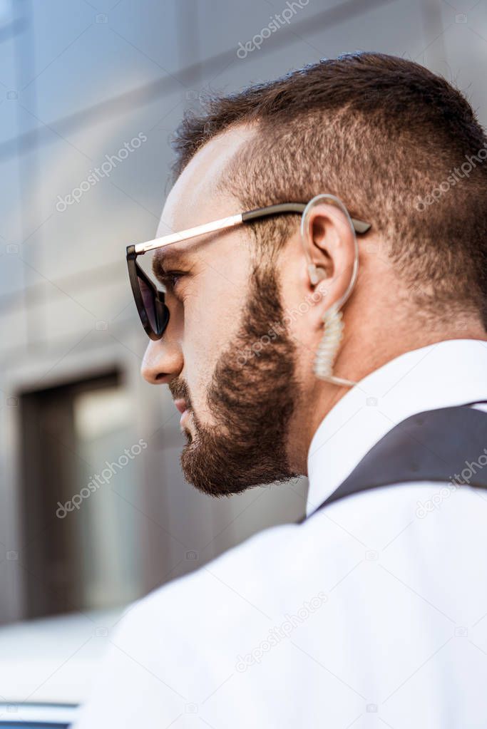 side view of handsome security guard with security earpiece on street