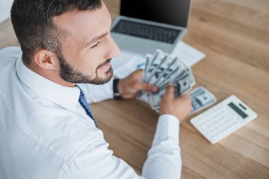 high angle view of financier counting cash with calculator in office clipart