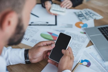 Yatırımcı Office masada smartphone kullanarak resim kırpılmış