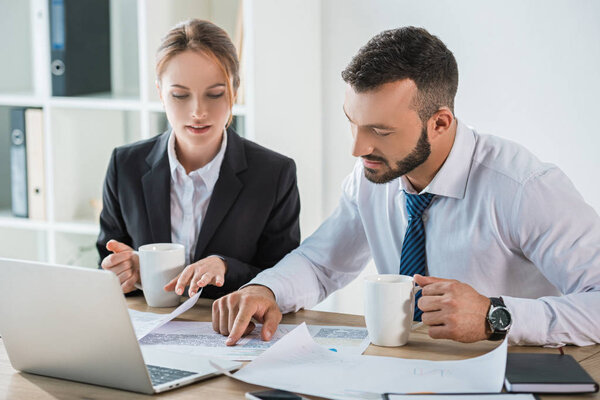 финансисты, работающие с документами во время перерыва на кофе в офисе
