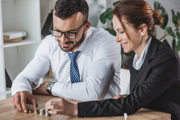 happy financiers stacking coins on table in office