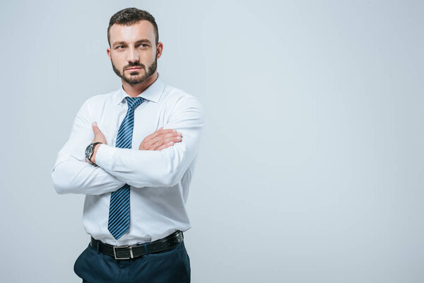 handsome businessman standing with crossed arms isolated on grey