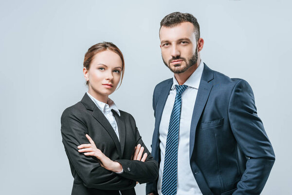businesswoman and businessman looking at camera isolated on grey