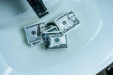 elevated view of dollar banknotes in water in sink clipart