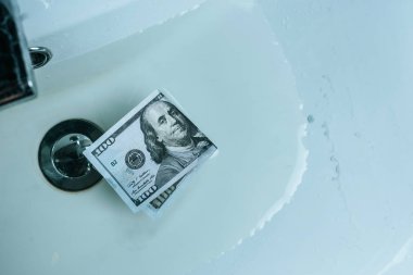 top view of dollar banknote in water in sink clipart