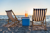 frissítő italok a hűvösebb és a hintó társalgók homokos tengerparton naplementekor 