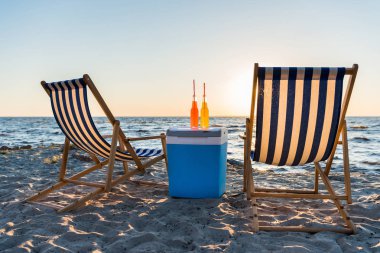 içecek soğutucu ve chaise Lounge kumsalda gün batımında yenileniyor 