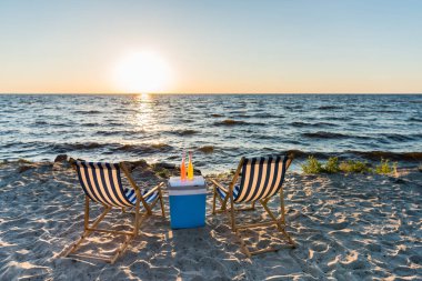 gün batımında kum plajındaki yaz içecekler soğutucu ve chaise Lounge üzerinde 