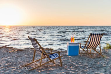 summer drinks on cooler and chaise lounges on sandy beach at sunset  clipart