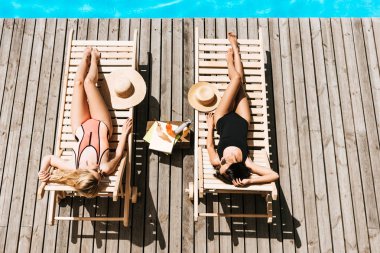 Genç kadınların şezlong Yüzme Havuzu yakınındaki bronzlaşma üstten görünüm 