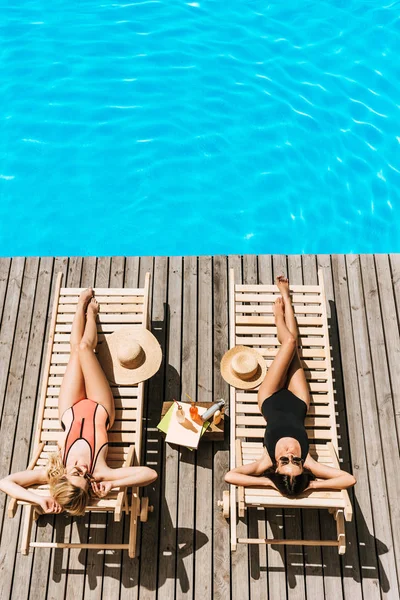Hoge Hoekmening Van Jonge Vrouwen Looien Chaise Lounges Bij Zwembad — Stockfoto