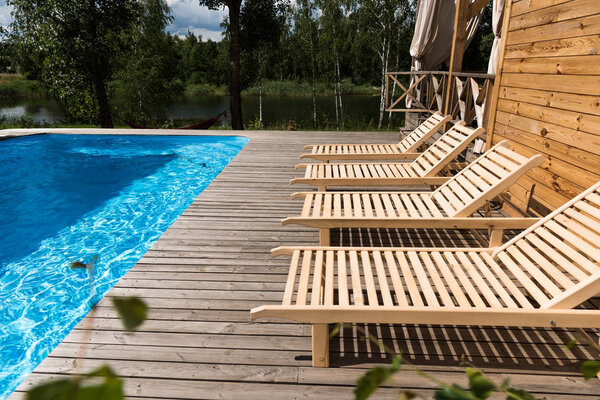 empty cozy chaise lounges near swimming pool  