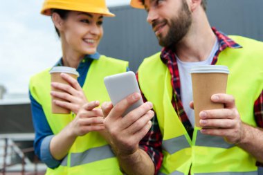 Mimarlar Emanet yelek ve kask kahve molası smartphone kullanarak  