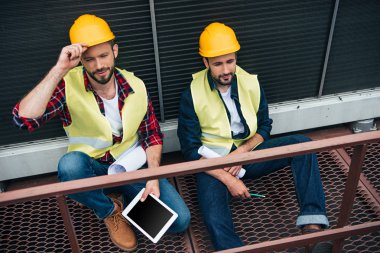 Mimarlar planları ve dijital tablet inşaat oturan