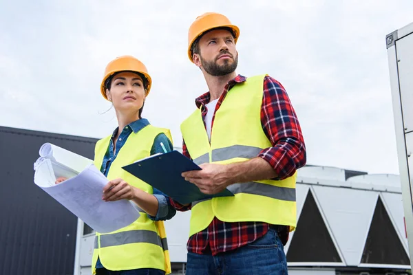 Konstrukteure Hardhats Arbeiten Mit Bauplänen Und Klemmbrett Auf Dem Dach — Stockfoto