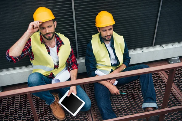 Mimarlar planları ve dijital tablet inşaat oturan