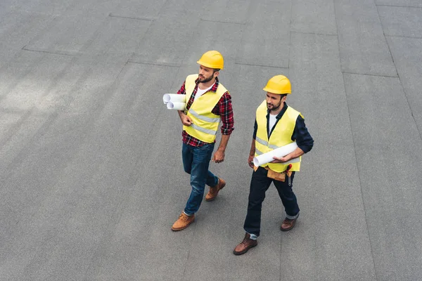 建筑师在安全背心和 Hardhats 的顶上的看法与蓝图 — 图库照片