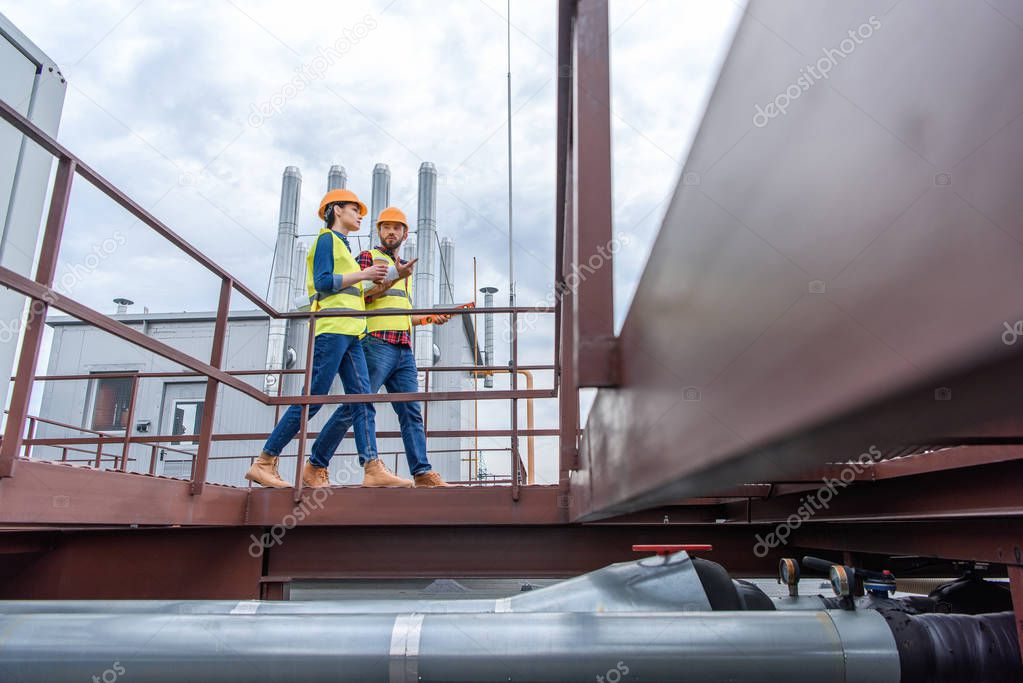 professional engineers in safety vests and helmets walking on roof 