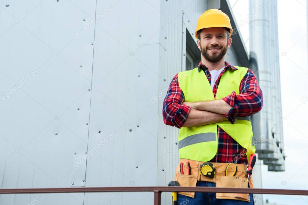 male professional engineer with tool belt posing with crossed arms