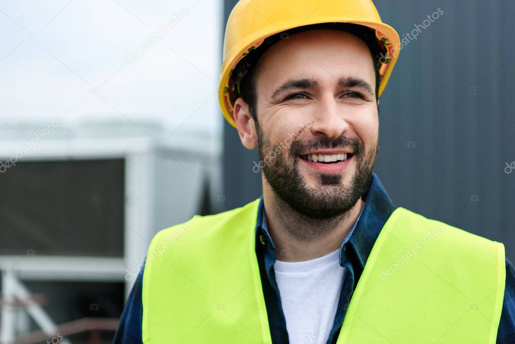 portrait of cheerful male engineer in safety vest and helmet
