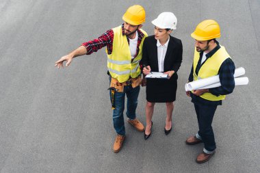 overhead view of female engineer and male workers with clipboard and blueprints pointing at construction clipart
