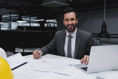 Erkek mimar planları ve laptop çalışma gülümseyen 
