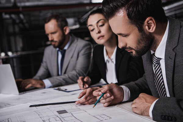 architects and engineers in suits working with blueprints together