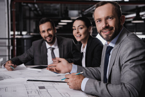 male and female engineers in suits working with blueprints together