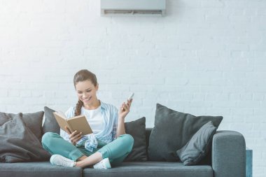 kadın uzaktan kumanda ile Klima açma kitap okuma