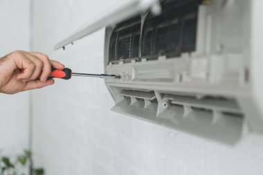 partial view of male worker repairing air conditioner with screwdriver clipart