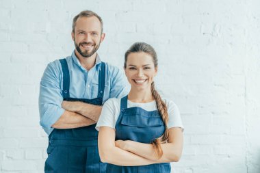 confident workers in overalls posing with crossed arms