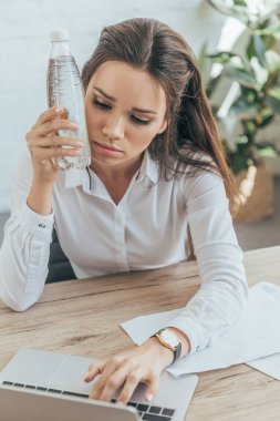 işkadını sıcak ofiste dizüstü kullanarak ve kendini soğuk şişe su soğutma