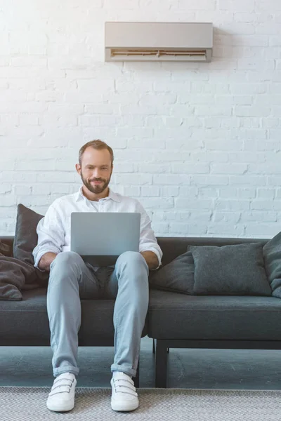 Handsome Bearded Man Using Laptop Sofa Air Conditioner Wall — Stock Photo, Image