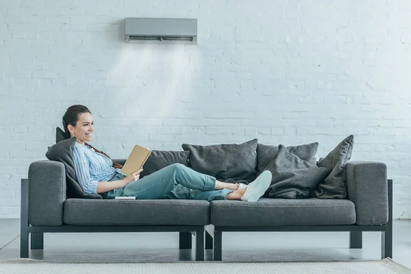 Woman Reading Book Couch Air Conditioner Blowing Her — Stock Photo, Image