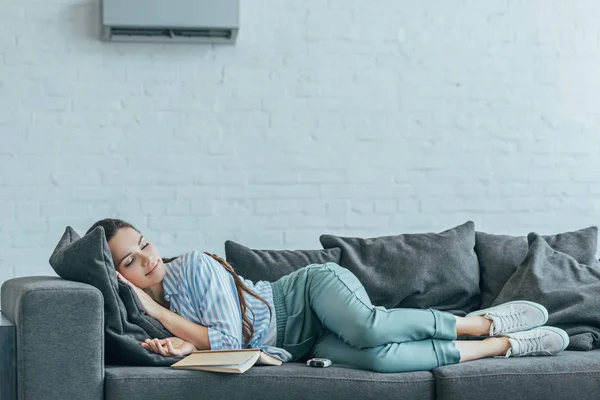 Γυναίκα Ύπνο Στον Καναπέ Βιβλίο Και Κλιματιστικό Στον Τοίχο — Φωτογραφία Αρχείου
