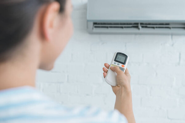 selective focus of woman with remote control  turning on air conditioner  
