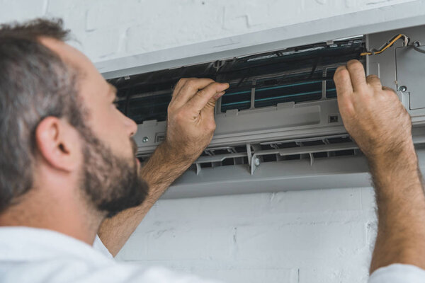 male bearded worker repairing air conditioner