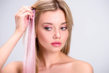 stylish young woman applying pink clip-on hair strand isolated on grey clipart