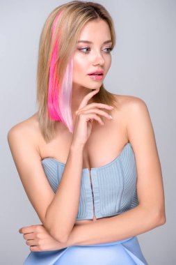 attractive young woman with colored hair strands and stylish corset looking away isolated on grey clipart