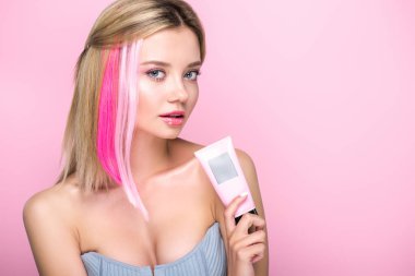 güzel genç kadın ile saç maskesi tüp tutarak ve pink izole kamera bakarak renkli saç ayrılmaktadır