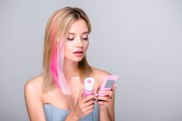 beautiful young woman with colored bob cut holding hair care supplies isolated on grey