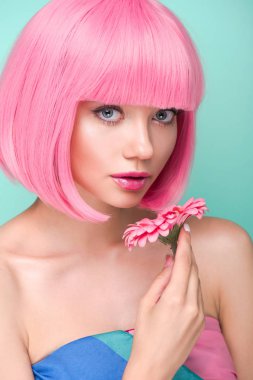yakın çekim çiçek tutan ve turkuaz üzerinde izole kamera bakarak pembe bob kesim ile güzel genç kadın portresi