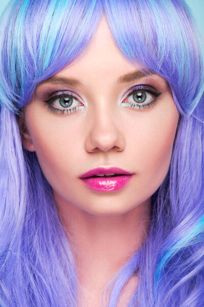 close-up portrait of sensual young woman with blue hair looking at camera isolated on blue