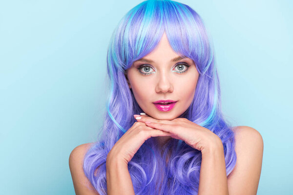 stylish young woman with blue hair looking at camera isolated on blue